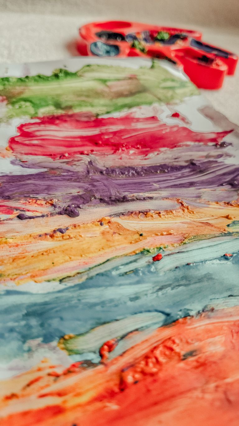 Close-up of a vibrant abstract painting with visible brush strokes and artist palette.